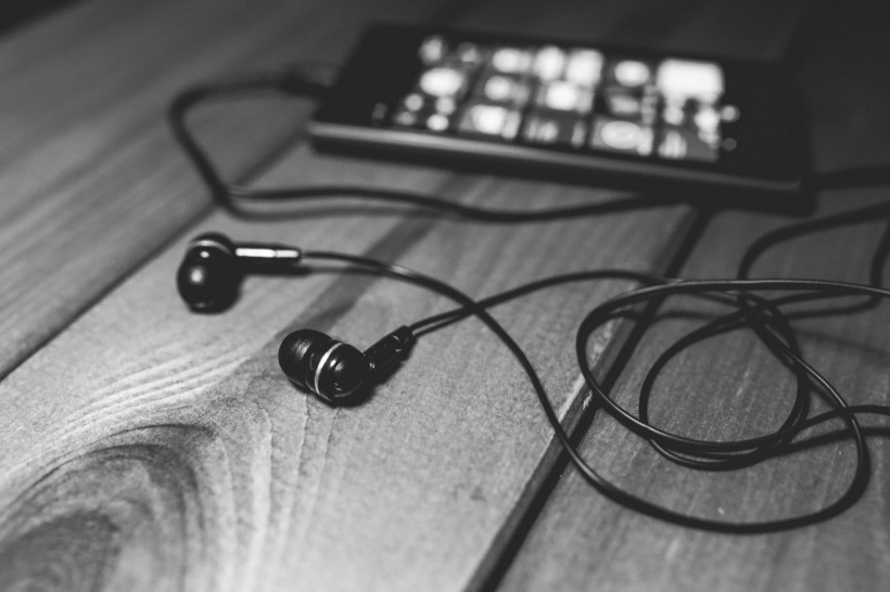 sw-Foto, ein MP3-Player mit Kopfhörern liegt auf einem Holztisch